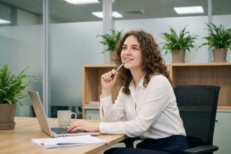 Jeune femme souriante au bureau avec ordinateur et documents