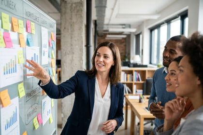 Femme manager présentant une stratégie de marque employeur à son équipe dans un bureau moderne avec tableau blanc et notes de travail